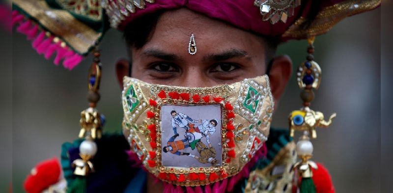 A participant in traditional costume wearing a mask featuring "COVID-19 warriors" as he attends a rehearsal for Garba, a folk dance, ahead of Navratri, a festival during which devotees worship the Hindu goddess Durga and youths dance in traditional costumes, amidst the coronavirus disease outbreak, in Ahmedabad, India, September 18, 2020. REUTERS/Amit Dave TPX IMAGES OF THE DAY
